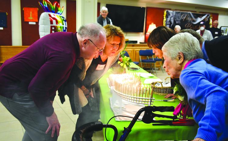 Megan Broome/The Clayton Tribune. Allie Moseley, right, blows out 100 candles on her birthday cake with help from friends and family members Bo Cribbs, Debby Moseley, and Cindy Wallis. Friends and family members gathered for Moseley’s centennial birthday party on Dec. 5. 