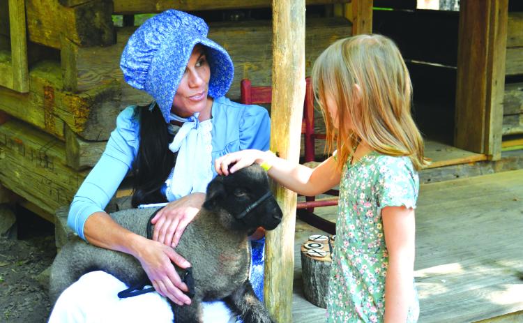 Enoch Autry/The Clayton Tribune. The annual Heritage Days event returned on June 9 and 10 at the Foxfire Museum and Heritage Center. Pictured, Stephanie Branch talks with Ally St. German as the 6-year-old pets “Hampshire” the lamb. Left: Enoch Autry/The Clayton Tribune. Sisters Anna, 7, and Claire, 4, Miller play inside one of the small Foxfire structures that were built for children.