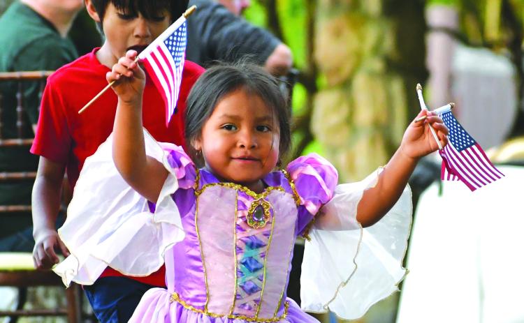 Megan Broome/The Clayton Tribune. Annalia Contreras, 3, waves American Flags in excitement and passes them out to visitors to The Dillard House for the Memorial Day weekend event on the Oaklawn Sunday, May 28. Behind her is her big brother Mateo Contreras, 6. 
