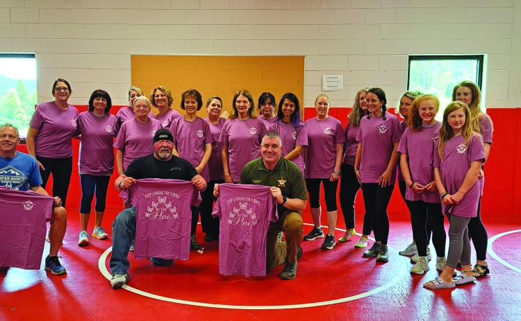 Megan Broome/The Clayton Tribune. Participants in the Rabun County Sheriff’s Office Ladies’ Self-Defense Class hold up pink shirts with butterflies that read “Stop looking for a hero, Be the Hero” at the last class May 27. Also  pictured are instructor Lt. Mark Gerrells and Sheriff Chad Nichols. 