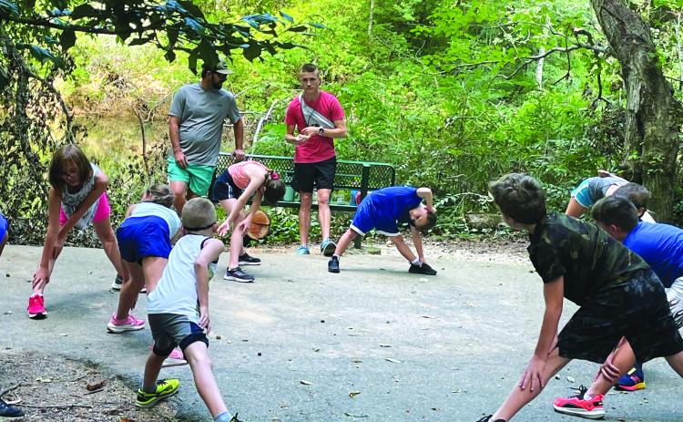 Submitted. Rabun County Recreation Department cross country head coach Ed Edison (center) has his young runners stretch before the start of practice.