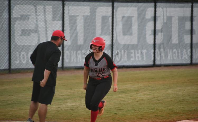Wade Cheek/The Clayton Tribune. Lady Cat catcher Chloe Erlewine smiles as she rounds third base past RCHS head coach Wesley Satterfield after she homers on Oct. 19.