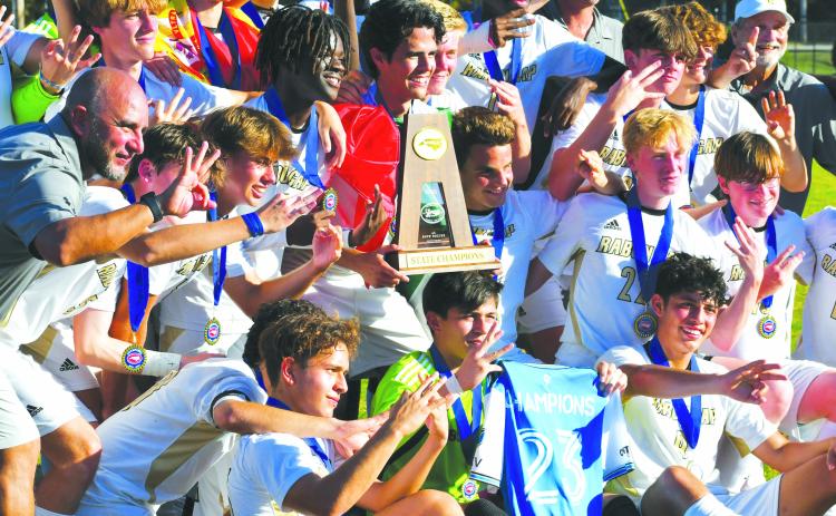Wade Cheek/The Clayton Tribune. THRICE IS SO NICE: Rabun Gap players and coaches hold up three fingers and the state soccer title trophy after winning the championship again.