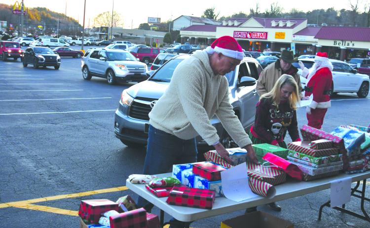 Enoch Autry/The Clayton Tribune.  Food Bank of Northeast Georgia Branch Manager James Brim and Victoria Anderson help with the presents that are given out to the children at the outdoor event in the Covered Bridge Shopping Center. 