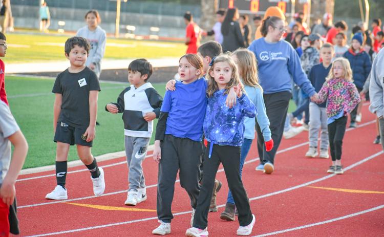 Wade Cheek/The Clayton Tribune. Youth soccer Lady Cats Juliette Pitassi (left) and Reeves Bragg walk arm-in-arm around Frank Snyder Memorial Stadium as part the March 19 “Rec Night” in between the RCHS girls and boys soccer games. 